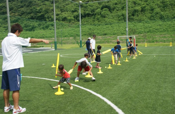 小学生にクリケットを教えている画像