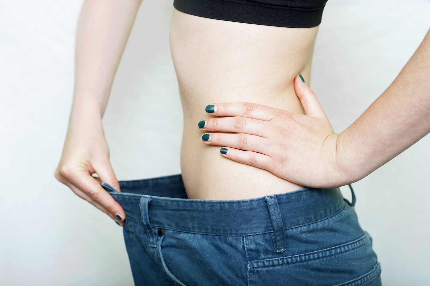 青いマニキュアをした女性がジーンズを履いています